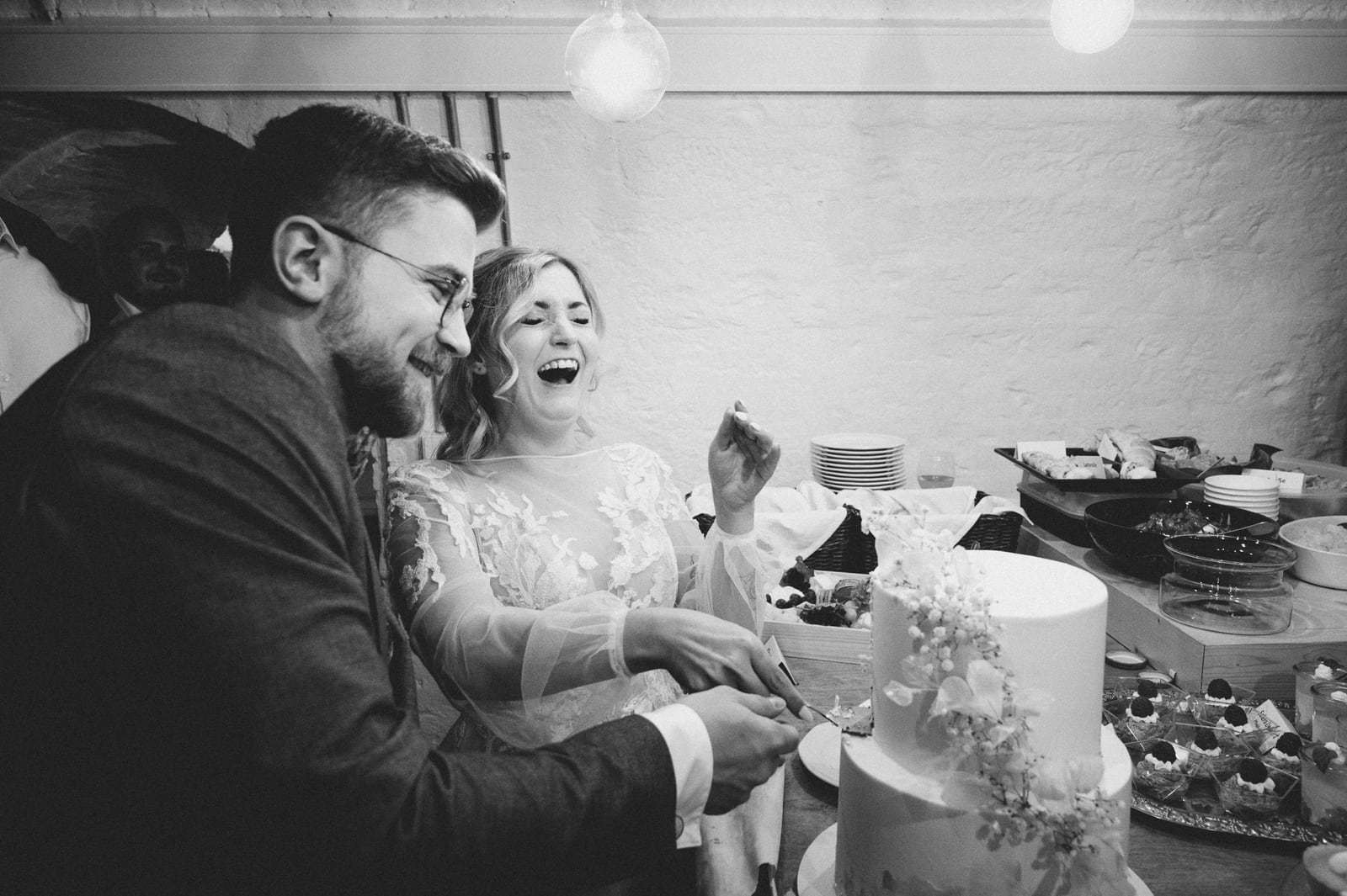 Tamara und Kevin lachen beim Anschneiden ihrer Hochzeitstorte